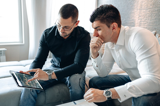 "Two businessmen analyzing projections and data analytics on a large screen."