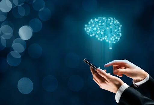 Image of a person holding a phone against a vibrant blue background. The phone screen displays a mesmerizing projection of a human brain composed of tiny cells. The intricate cellular structure of the brain symbolizes knowledge, intelligence, and the power of technology to unlock our understanding of the human mind. The projection extending beyond the phone screen represents the limitless potential and connection between digital technology and our cognitive abilities.