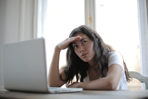 "Image of a girl sitting in front of a computer, displaying signs of stress and fatigue. Her face carries a weary expression, with visible signs of exhaustion. The tense posture and weary gaze indicate the impact of long hours or high-pressure work on her well-being. The image serves as a reminder of the importance of self-care and managing stress in the digital age.